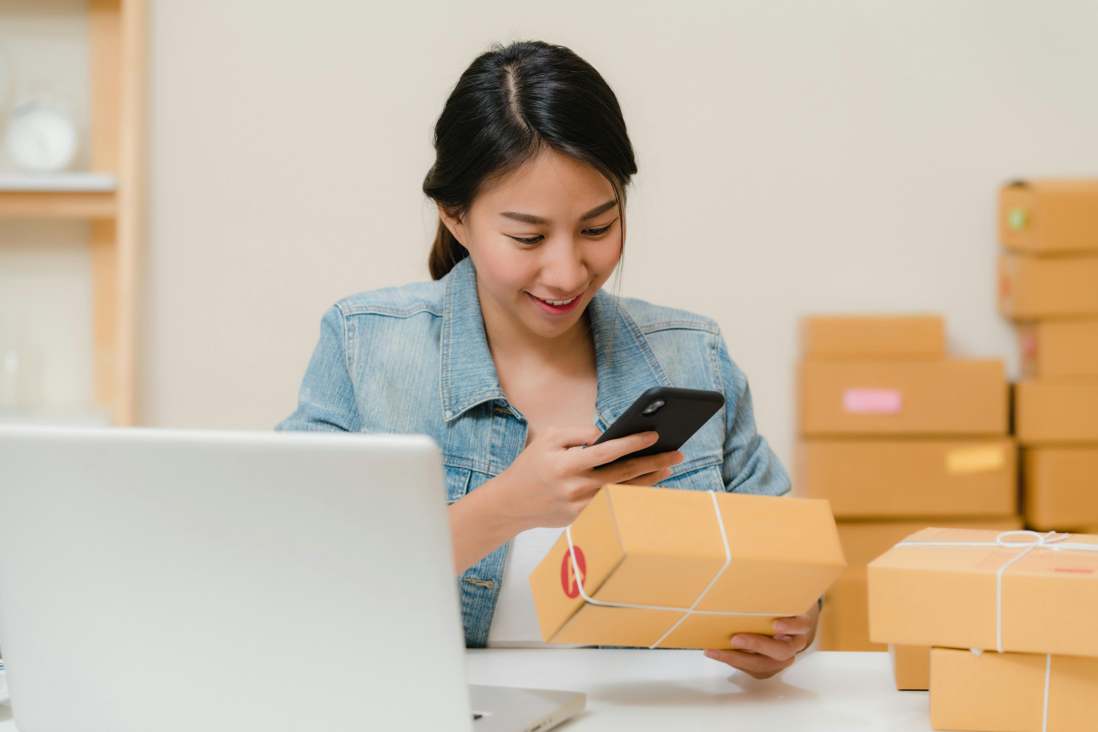 Người bán hàng online kiểm tra đơn hàng bên hộp và điện thoại
